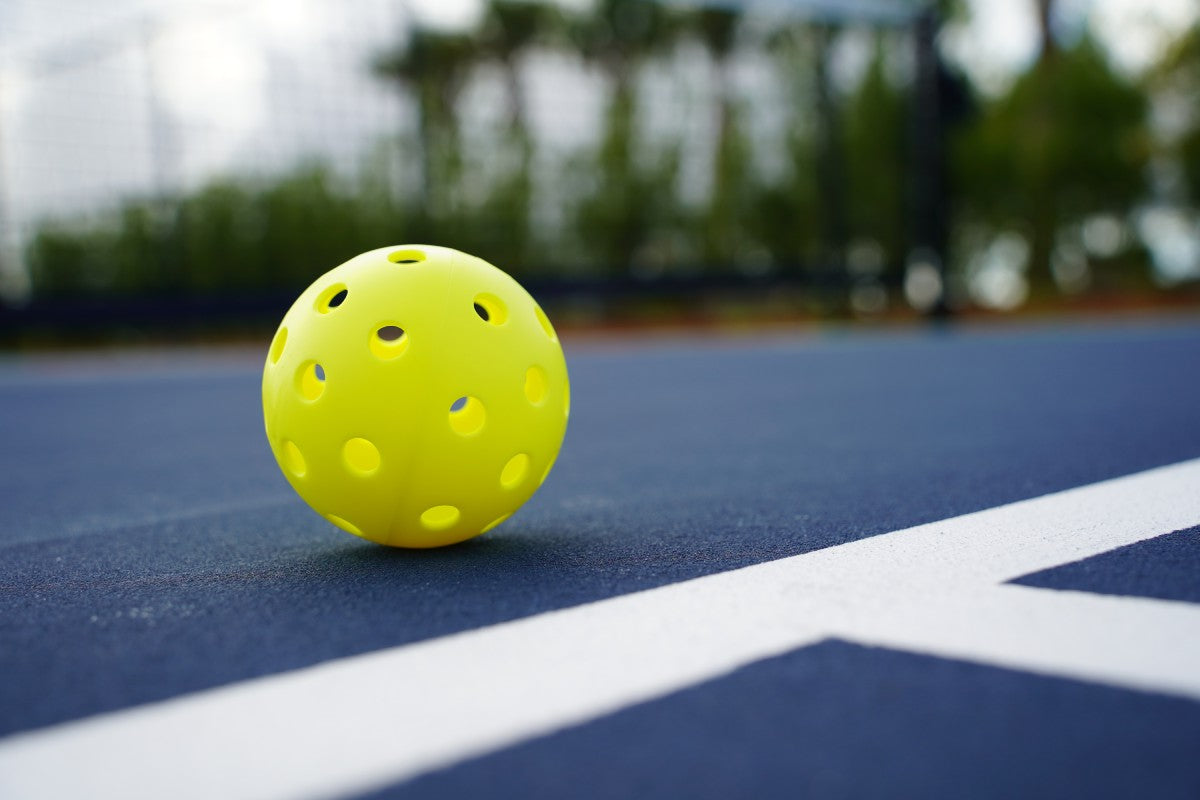 A close up of a pickleball on a court.