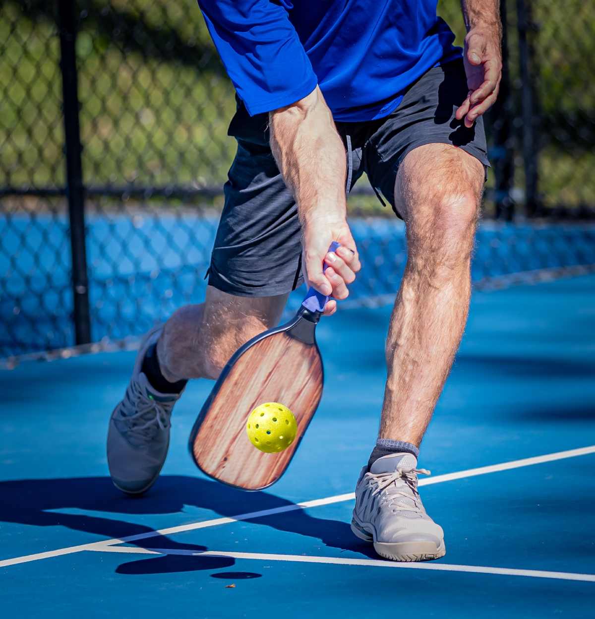 A pickleball player hits a low volley shot.