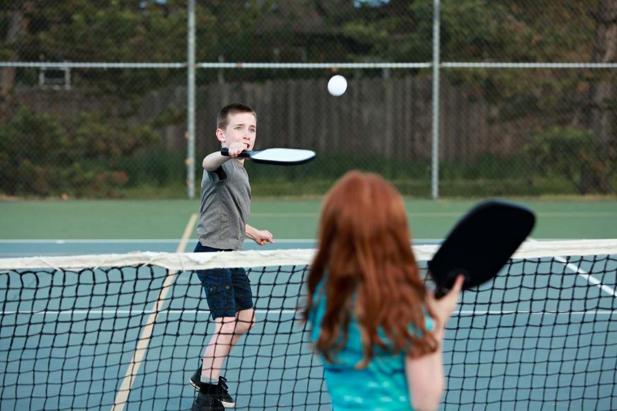 Two children play pickleball on their school’s pickleball court