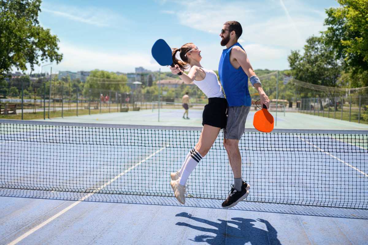 A couple chest bumps while partnering in a game of pickleball 