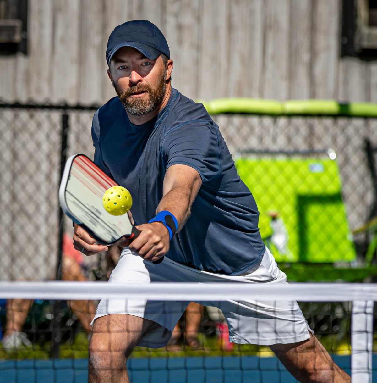 A pickleball player reaches to make a shot on the court. 