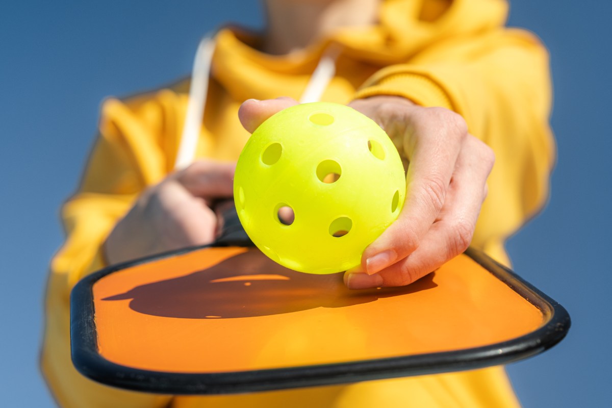 A pickleball player holds a ball to her paddle’s face