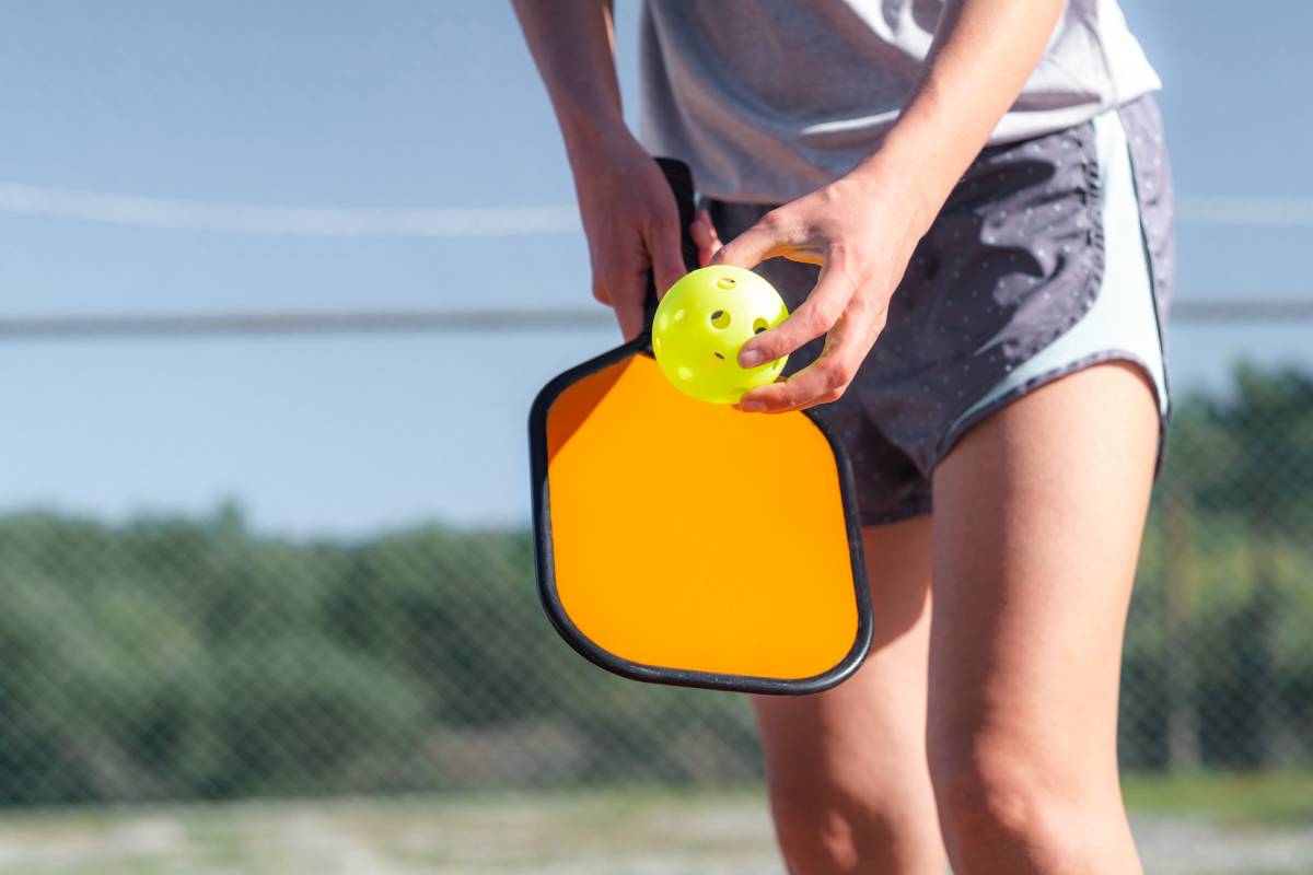 A pickleball player prepares to serve the ball.