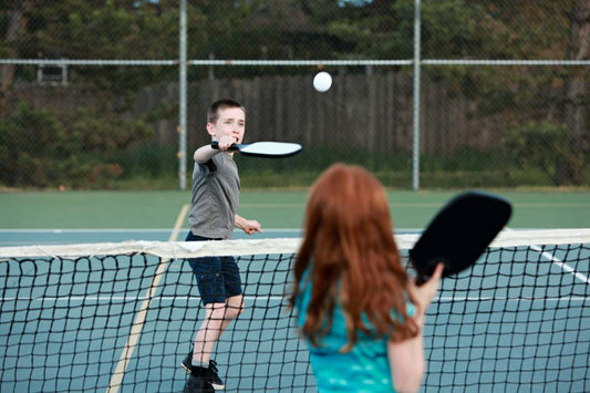 Two children play pickleball on their school’s pickleball court 