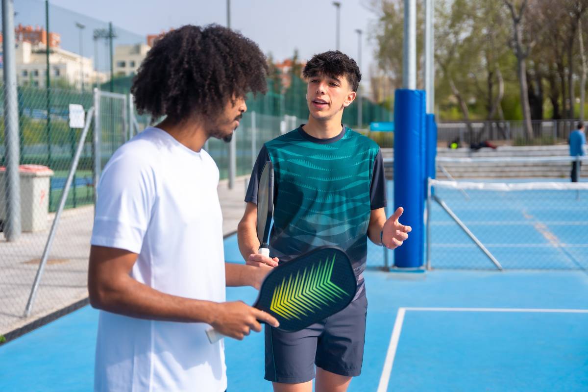 Two players on a pickleball doubles team talk strategy before the next serve.