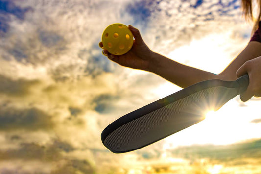 A pickleball player prepares to serve the ball.