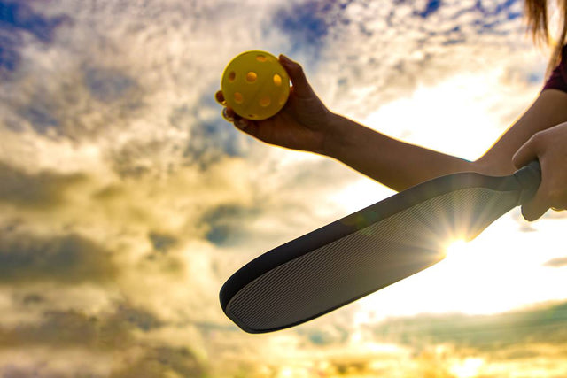 A pickleball player prepares to serve the ball.