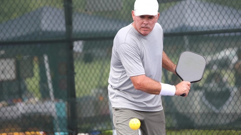 old man playing pickleball in the court
