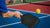 over the shoulder shot of man hitting a pickleball with a paddle