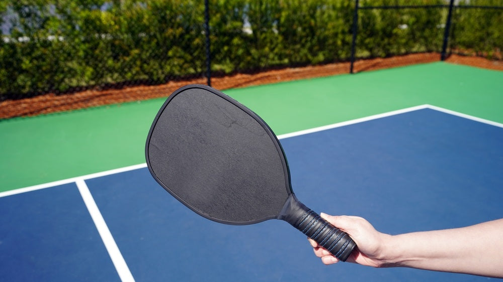 person holding pickle ball paddle on court